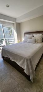 um quarto com uma cama grande e uma janela grande em Departamento Confortable y Moderno en Acapulco Diamante em Acapulco