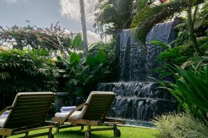 zwei Gartenstühle vor einem Wasserfall in der Unterkunft The Lotus Residence by Amerta Experience in Tabanan