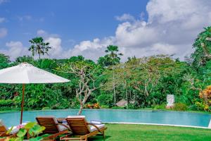 a group of chairs and an umbrella next to a pool at Lotus Residence Tabanan in Tabanan