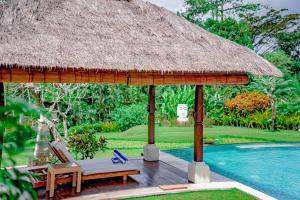 a resort with a pool and a straw umbrella and chairs at Lotus Residence Tabanan in Tabanan