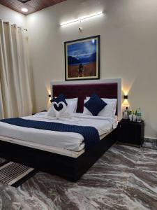um quarto com uma cama grande e almofadas azuis e brancas em The Corbett Jungle By JitaInn em Rāmnagar