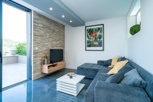 a living room with a blue couch and a tv at Apartments Villa Arcadia in Dubrovnik