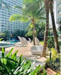 ein Resort mit Palmen und Stühlen sowie einem Gebäude in der Unterkunft Adam's Crib Apartment 2BR by Azure Residences Near Airport in Manila