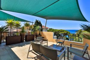 a patio with a table and chairs and a green umbrella at Hôtel Provençal in Bandol