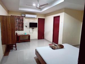 a bedroom with a bed and a desk and a television at Hotel Chanma International in Coimbatore