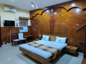 a bedroom with a large bed with a wooden headboard at Hotel Chanma International in Coimbatore