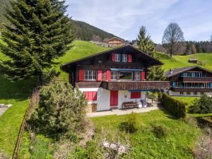 ein Haus mit roten Türen auf einem grünen Hügel in der Unterkunft Apartment Zita - GRIWA RENT AG in Grindelwald