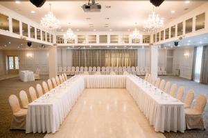 uma configuração para um casamento em um salão de baile com mesas e cadeiras brancas em Cosmonaut em Karaganda