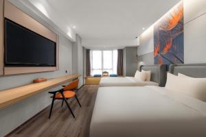 a hotel room with two beds and a flat screen tv at Manju Hotel in Nantong