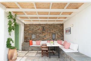 a patio with a table and chairs and a stone wall at Casa Xyla-sunset view villa in Melissaki