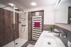 ein Bad mit einer Dusche und einem weißen Waschbecken in der Unterkunft Alpenherz Apartments in Sankt Gallenkirch