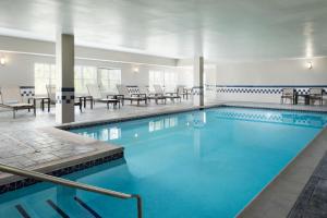 a swimming pool with tables and chairs in a building at Residence Inn Mount Olive At International Trade Center in Stanhope