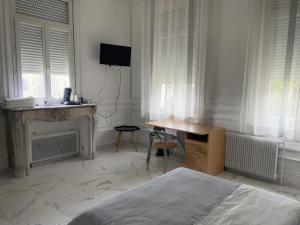 a bedroom with a bed and a desk and windows at Room in Calais