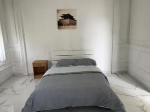 - un lit dans une chambre blanche avec une photo sur le mur dans l'établissement Room, à Calais
