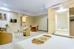 LepoleopにあるSahid Azizah Syariah Hotel and Convention Kendariのベッドとリビングルームが備わるホテルルームです。