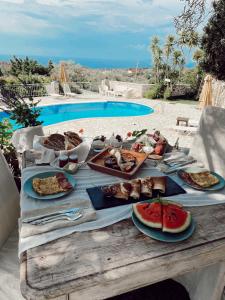 una mesa con platos de comida junto a una piscina en Villa Elenia, en Tsoukaladhes