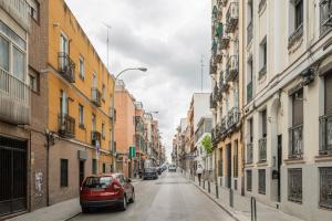 Une voiture rouge qui descend dans une rue avec des bâtiments dans l'établissement dobohomes - Juan de Olias, à Madrid