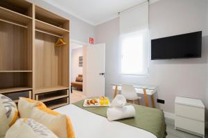 Cette chambre comprend un lit, un bureau et une télévision. dans l'établissement dobohomes - Juan de Olias, à Madrid