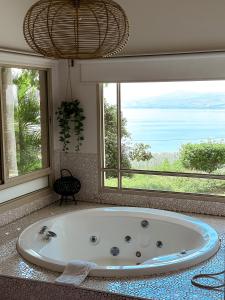 uma grande banheira na casa de banho com janelas em The White Chalet View em Moshav Ramot