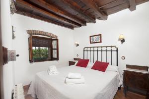 1 dormitorio con 1 cama con sábanas blancas y almohadas rojas en La Jara · Apartamentos Rurales, en Serrejón