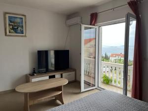a bedroom with a television and a window with a view at Apartments Cvjetković in Mlini