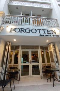 a front of a hotel with two tables and a balcony at Forgotten Hostel Silom in Bang Rak