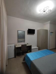 a bedroom with a bed and a desk and a television at Albergo Primavera in Porto Cesareo