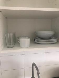 a kitchen shelf with plates and bowls and a sink at Nice Entire Semi - Attached House - B in Umeå