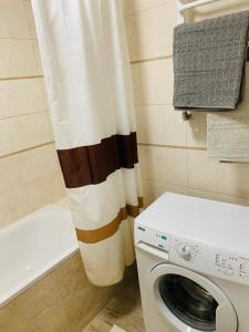 y baño con cortina de ducha y lavadora. en Центр. Поруч озеро та парк (5), en Ternopilʼ