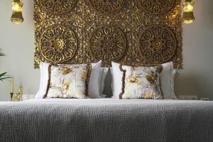 a bed with a gold headboard and pillows at Pafsilipon Suites in Ermoupoli