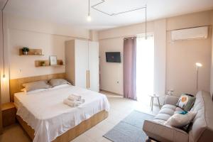 a bedroom with a white bed and a couch at PeramoBello in Nea Peramos