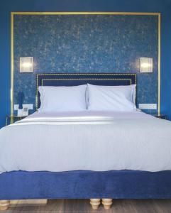 a bedroom with a large bed with a blue wall at Pafsilipon Suites in Ermoupoli