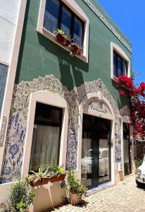a green building with windows and potted plants on it at Charming Portuguese style apartment, for rent "Vida à Portuguesa", "Amêndoa or Limão" Alojamento Local in Portimão