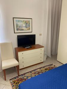 ein Schlafzimmer mit einer Kommode mit einem Stuhl und einem TV in der Unterkunft Case vacanze Dalia in Torregrotta