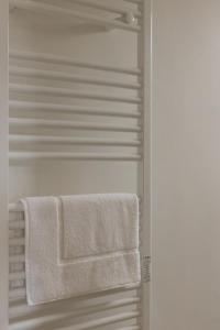 - une serviette blanche suspendue à un porte-serviettes dans la salle de bains dans l'établissement Lovely Rooms - Guest House Suites, à Triggiano