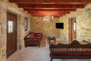- un salon avec deux canapés et une télévision dans l'établissement Draganigo Luxury Stone Houses 40 min from Matala, à Áno Moúlia