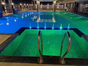 a large swimming pool with lights in the water at Royal Palace Beach Resort in Mandarmoni