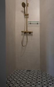 a bathroom with a shower with a black and white tile floor at Pafsilipon Suites in Ermoupoli