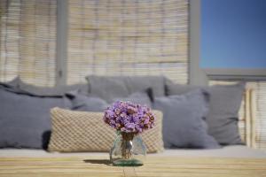 a glass vase with purple flowers sitting on a table at Pafsilipon Suites in Ermoupoli