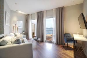a living room with a white couch and a large window at Pafsilipon Suites in Ermoupoli