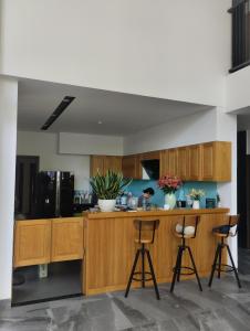 a kitchen with wooden cabinets and two bar stools at La Maison De Fleurs in Da Nang