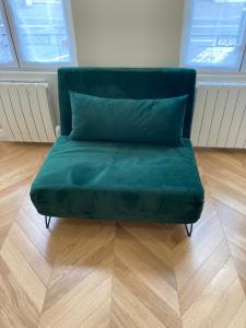 a green couch sitting on top of a wooden floor at Le Cottage du Château - INSEAD-Grand Parquet in Fontainebleau