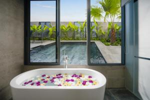 Estrella Boutique Hotel في دا نانغ: حمام مع حوض استحمام مع الزهور