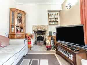 a living room with a large television and a fireplace at River Cottage in Two Dales
