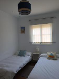 two beds in a room with two windows at Villa Ostrero in Chiclana de la Frontera