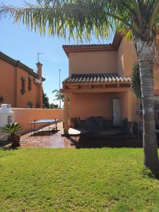 une maison avec un palmier dans la cour dans l'établissement Villa Ostrero, à Chiclana de la Frontera
