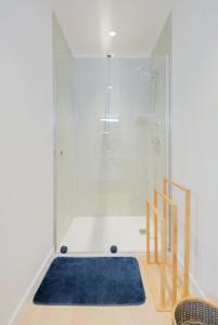 een badkamer met een douche en een blauw tapijt bij Appartement Balcon Garage Centre Gare in Nancy