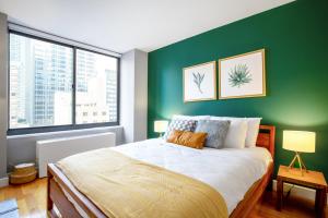a bedroom with a green wall with a bed and two windows at 1BR nr Times Sq w Indoor pool Gym NYC-141 in New York