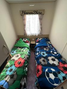 two beds in a small room with a window at 8 berth caravan Presthaven Sands in Talacre