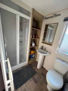 a bathroom with a shower and a toilet and a sink at 8 berth caravan Presthaven Sands in Talacre